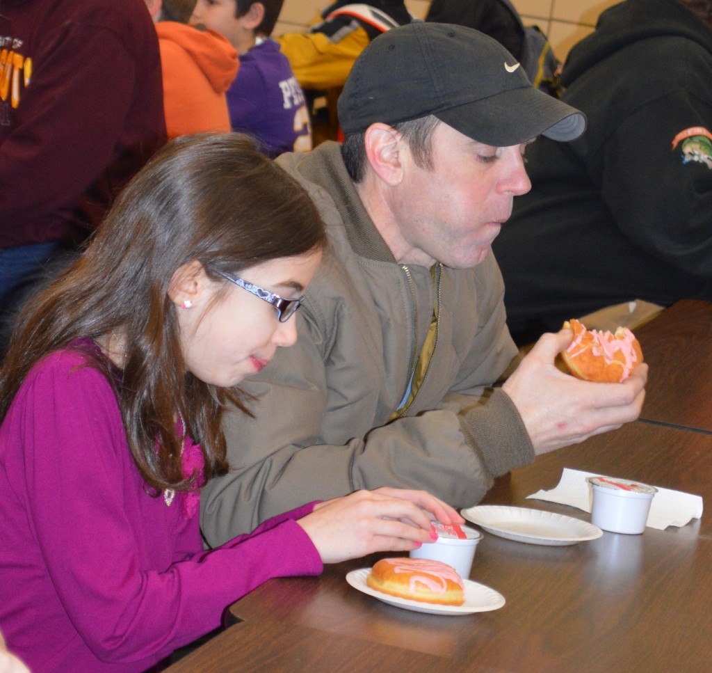 A BIG BITE of donut for dad Brigham Klassen, right, who was able to spend the special morning time with his daughter, Olivia, left, a fourth-grade student at Mountain Lake Public Elementary.