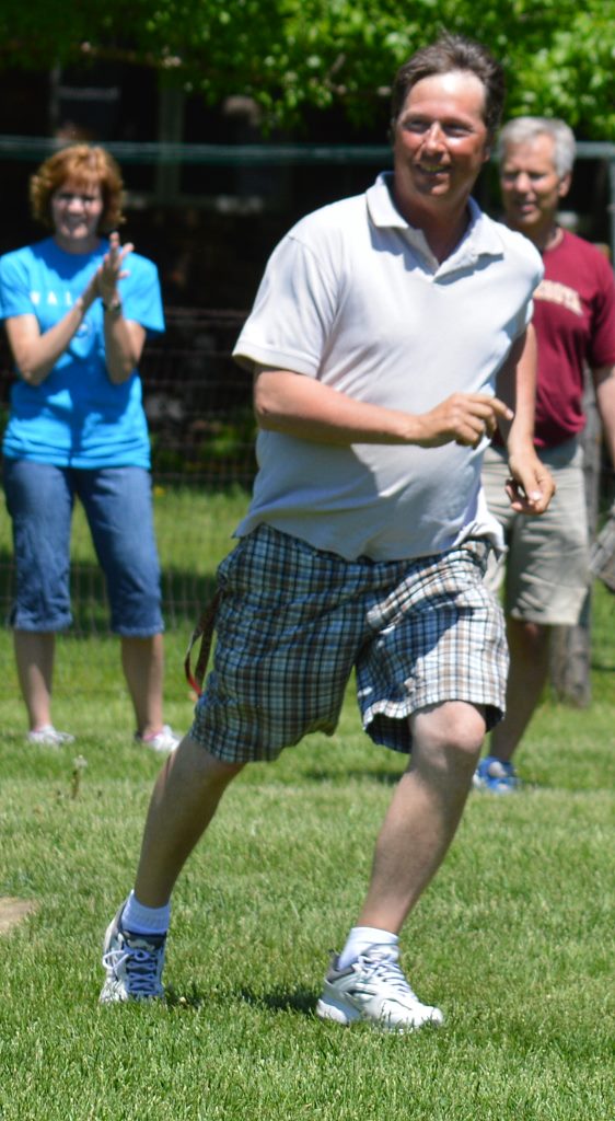 STAFF PITCHER AND special education (EBD) teacher Tim Snyder watches the play on his hit ball as he rounds first and motors towards second-base. Cheering him on in the background are his teammates, Stephanie Willaby, left, and Kyle Blomgren, right.
