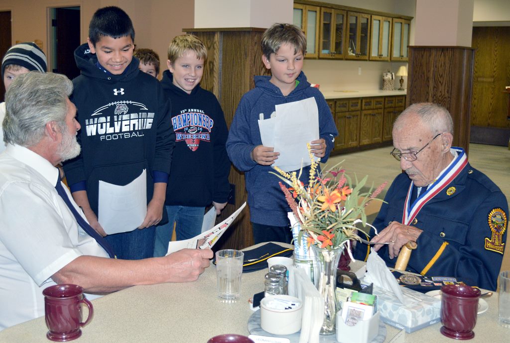 ADDITIONAL MOUNTAIN LAKE American Legion Post members, Jim Crawford, left and Dean Schied, right, receive "Thank Yous" from Jose Garnica, Noah Rempel and Brody Kleven. Additional American Legion members who presented a Veterans Day program were Bob Minion and Gerhard Quiring.